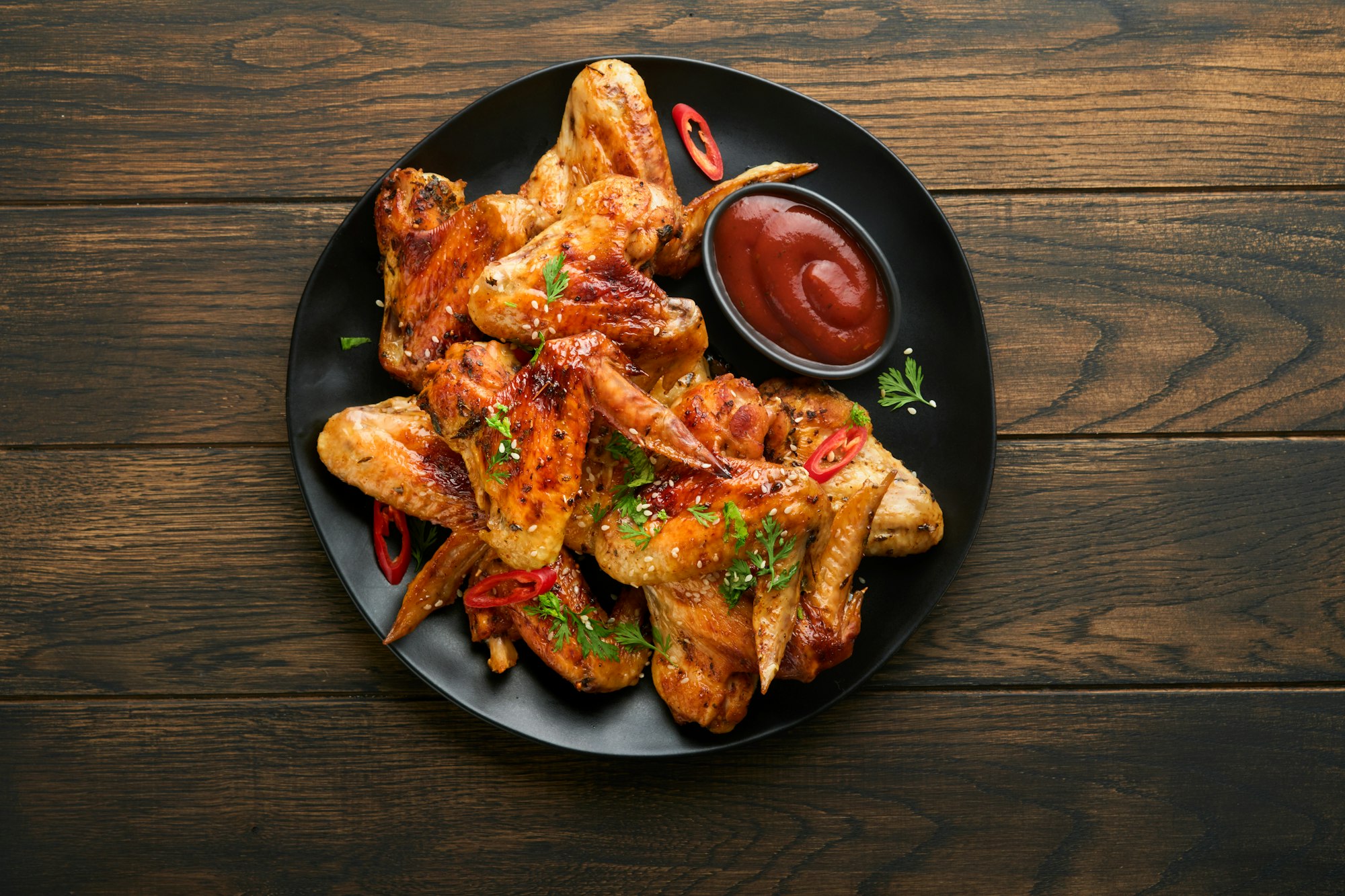 Chicken wings. Grilled or baked chicken wings with sesame seeds and ketchup or spicy tomato sauce on