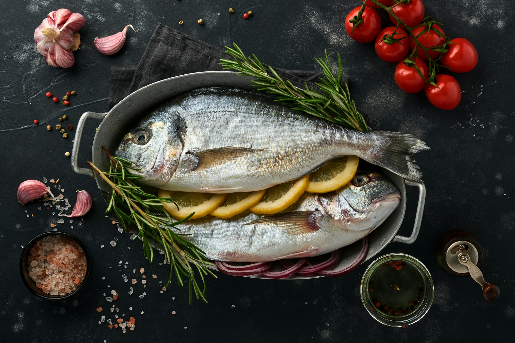 Raw dorado fresh fish or sea bream with ingredients for making lemon, thyme, garlic, cherry tomato a