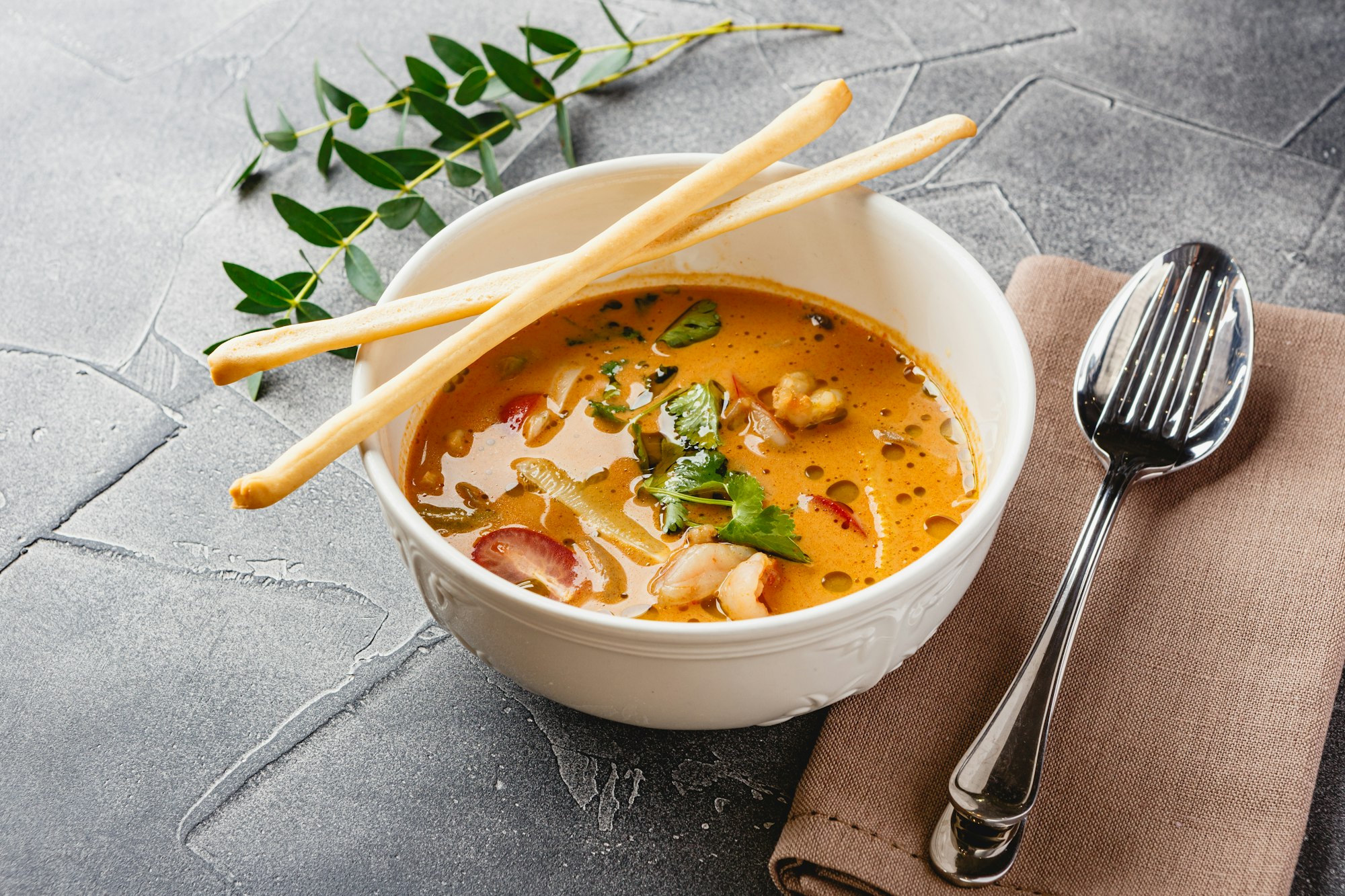 Tom Yam kung Spicy Thai soup with shrimp, seafood, coconut milk and chili pepper in bowl